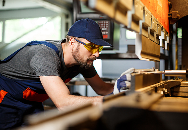 Portrait of worker near metalworking machine, steel factory background.